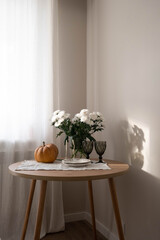 A warm and cozy autumn setting is beautifully adorned with Chrysanthemum flowers, a cheerful pumpkin, and festive bunting.