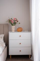 Transform your bedroom into a stylish space with a bouquet, decorative pumpkin, and chic, comfortable furniture.