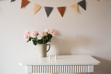A vase of pink roses and an elegant champagne glass, candles on a white table, ideal for any special celebration.