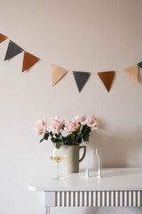 A vase of pink roses and an elegant champagne glass, candles on a white table, ideal for any special celebration.