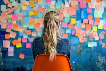 Woman facing a wall covered in colorful sticky notes, brainstorming or problem-solving, creative workspace.