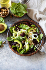 Couscous with avocado, beet, fresh spinach and dressing vinaigrette on a grey stone background. Healthy natural plant based vegetarian food, low calories dieting meal. Copy space.