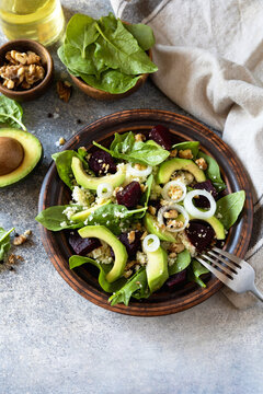 Couscous with avocado, beet, fresh spinach and dressing vinaigrette on a grey stone background. Healthy natural plant based vegetarian food, low calories dieting meal. Copy space.