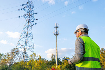 Male engineer maintains a telecommunications tower and power lines. Inspecting 4G and 5G network equipment. Control and maintenance of electrical installations for cellular communications.