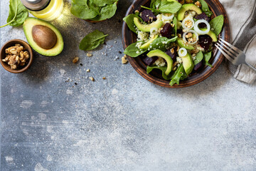 Couscous with avocado, beet, fresh spinach and dressing vinaigrette on a grey stone background. Healthy natural plant based vegetarian food, low calories dieting meal. View from above. Copy space.