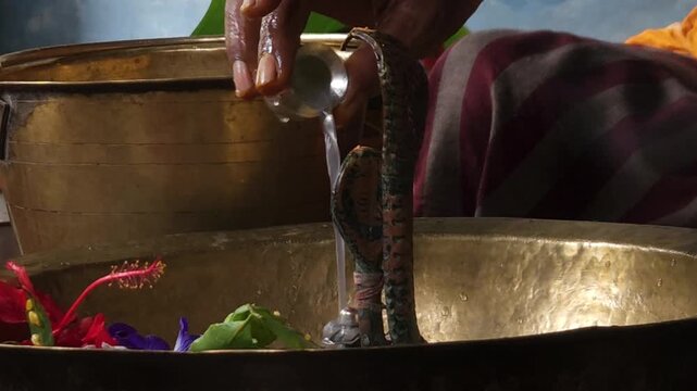 Close-up of Shivling pooja with milk, flowers, and bael leaves being offered. Indian people performing sacred havan on the occasion of Mahashivratri, offering ghee to the holy fire during  Vedic puja.