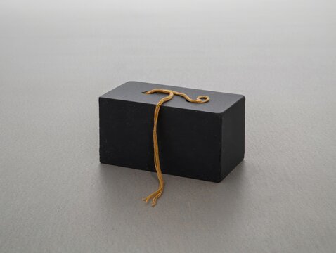 Small black box with gold string on gray surface