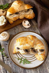 Freshly baked croissants with mushrooms and ricotta on rustic wooden table setting.