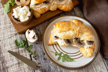 Freshly baked croissants with mushrooms and ricotta on rustic wooden table setting.