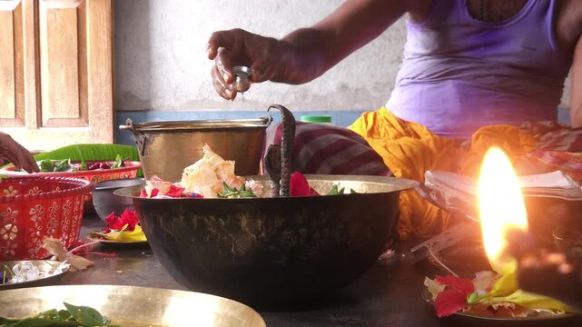 Close-up of Shivling pooja with milk, flowers, and bael leaves being offered. Indian people performing sacred havan on the occasion of Mahashivratri, offering ghee. Focused on background.