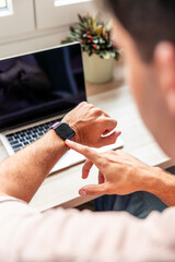 vertical Young man checking smartwatch during home teleworking