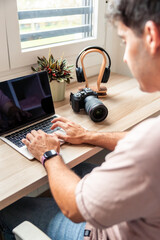 vertical Young man teleworking using laptop and camera