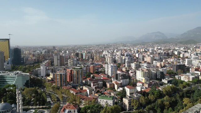 Aerial panorama of Tirana city, Albania, drone rotating 360 degrees over urban skyline with mountain backdrop and residential architecture