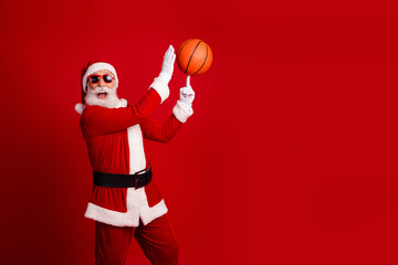 Santa Claus performing a fun basketball trick on a vibrant red background celebrating Christmas joy