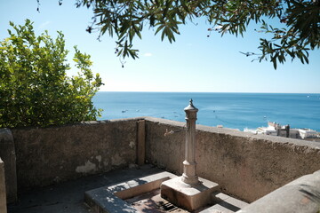 Panoramic view of the Amalfi coast, with a drinking fountain in the foreground.