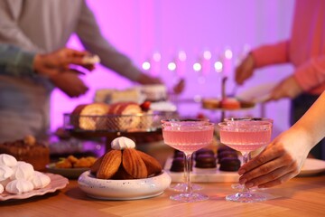 People with drinks and delicious desserts at buffet table, selective focus