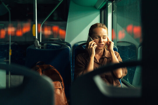 Woman talking on smartphone while commuting home by night bus