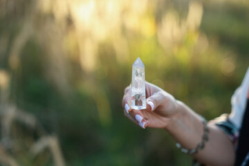 Woman meditating with crystal to heal or restore her aura outdoors, closeup. Space for text