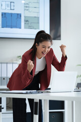 Professional woman looking excited after reading email on laptop
