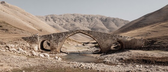 Ancient stone bridge over a serene river surrounded by arid mountains in a tranquil landscape