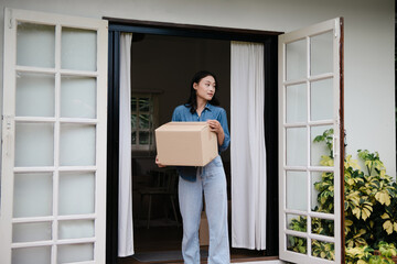 Asian woman moves cardboard boxes to relocate at her new home