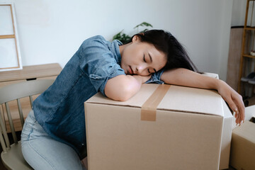 A woman exhaustedly organizes cardboard boxes for relocation to her new house