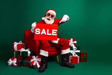 Santa Claus promoting holiday sales while dressed in a festive costume with presents and gestures on a green background