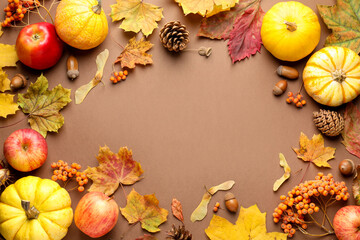 Dry autumn leaves, pumpkins, apples, acorns, pine cones and rowan berries on dark beige background, flat lay. Space for text