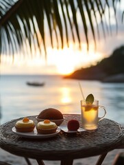 A small table with a coconut and mango tart and a cupcake on the beach at sunset featuring a glass of lemonade and palm leaves in Hawaii