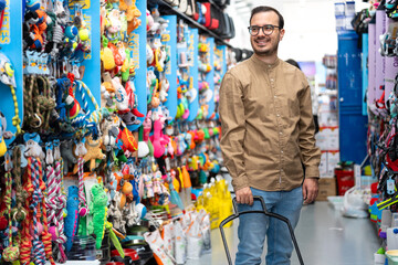 Smiling man shopping for pet supplies in store aisle