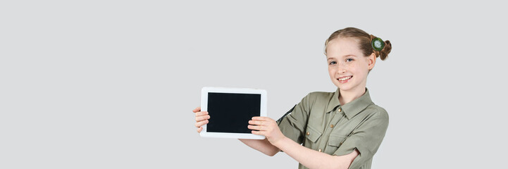 Caucasian young female smiling with blank screen tablet in casual outfit on gray background.