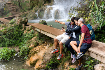 Friends trekking, taking selfie near waterfall