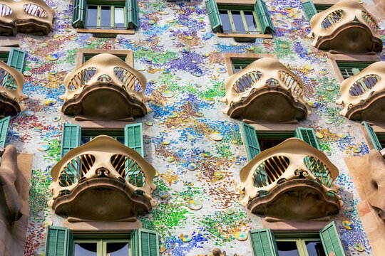 Barcelona, Spain - June 13, 2025: Casa Batllo colorful mosaic facade with organic balconies and green shutters in Barcelona. 