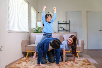 Happy family parents and child enjoying playful time together in living room, creating strong emotional bonds