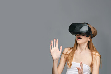 Young caucasian female experiencing virtual reality with vr headset on gray background.