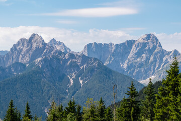 Obraz premium Majestic Julian Alps peaks, including Mangart and Jalovec, tower in the distance on a clear summer day. Stunning mountain landscape is viewed from the Dreiländereck, the tri-border of three countries.