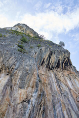 Majestic rocky cliffside against blue sky with sparse vegetation.