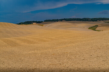 Obraz premium Farmhouse on Ploughed Tuscan Hill under Stormy Sky