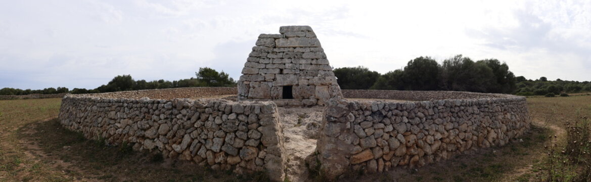 Panoramic view of  Naveta des Tudons. A prehistoric collective tomb  built with large dry stone forming an inverted boat. Talayotic Menorca. UNESCO word heritage site. Menorca, Balearic Islands, Spain