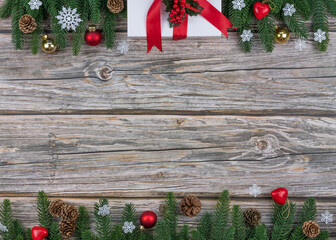 Christmas and New Year Frame on wooden background with fir branches, gift box, ornaments, and snowflakes