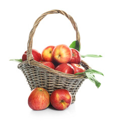 Fresh apples in wicker basket and green leaves isolated on white