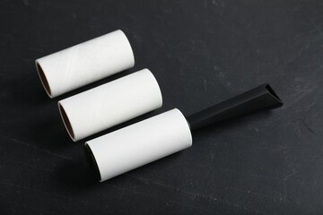 Lint roller and adhesive rolls on black table, closeup