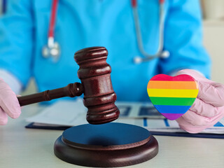 Health care professional holds rainbow heart and gavel representing LGBTQ rights and justice in medical settings