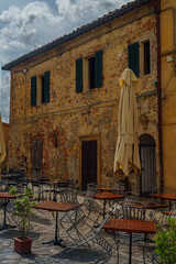 Medieval Tuscan Piazza with Stone Buildings, Empty Cafe Tables and Closed Umbrellas