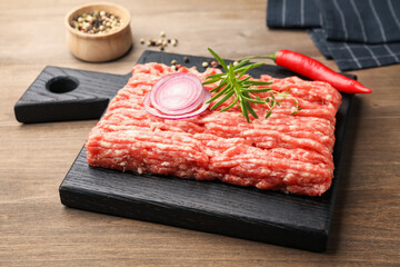 Raw minced meat with rosemary, thyme and spices on wooden table, closeup