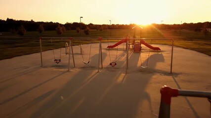 Empty Playground With Swings and Slides Bathed in Warm Golden Hour Sunset Light Casting Long Shadows on Sand Play Area Ideal for Childhood Nostalgia