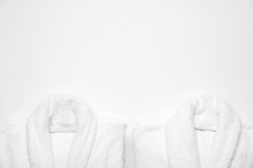 Soft bathrobes on white background, top view with space for text. Spa and relax