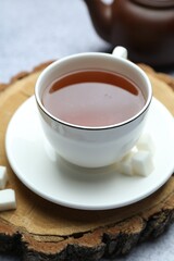 Aromatic black tea in cup and sugar on table, closeup