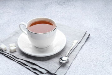 Aromatic black tea in cup, sugar and spoon on light grey table, closeup. Space for text