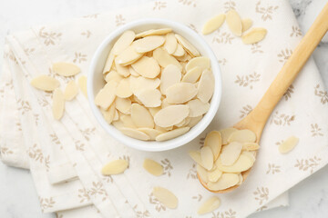 Fresh almond flakes on white table, top view